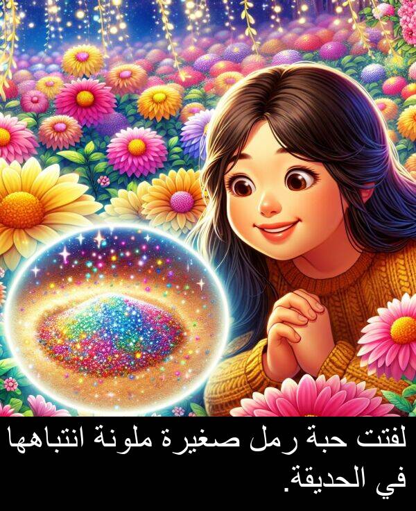 صغيرة: لفتت حبة رمل صغيرة ملونة انتباهها في الحديقة.