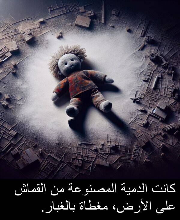 بالغبار: كانت الدمية المصنوعة من القماش على الأرض، مغطاة بالغبار.