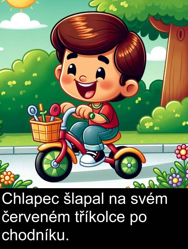 šlapal: Chlapec šlapal na svém červeném tříkolce po chodníku.