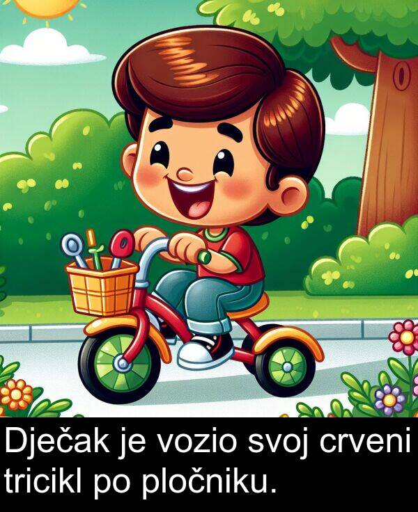 crveni: Dječak je vozio svoj crveni tricikl po pločniku.