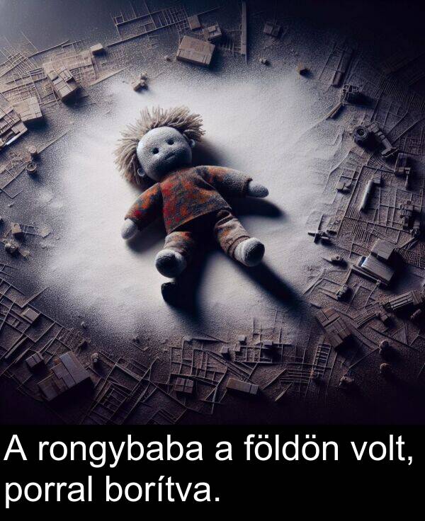 porral: A rongybaba a földön volt, porral borítva.