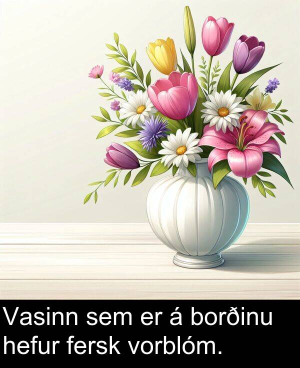 sem: Vasinn sem er á borðinu hefur fersk vorblóm.