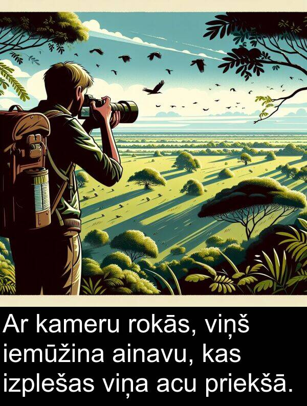 ainavu: Ar kameru rokās, viņš iemūžina ainavu, kas izplešas viņa acu priekšā.